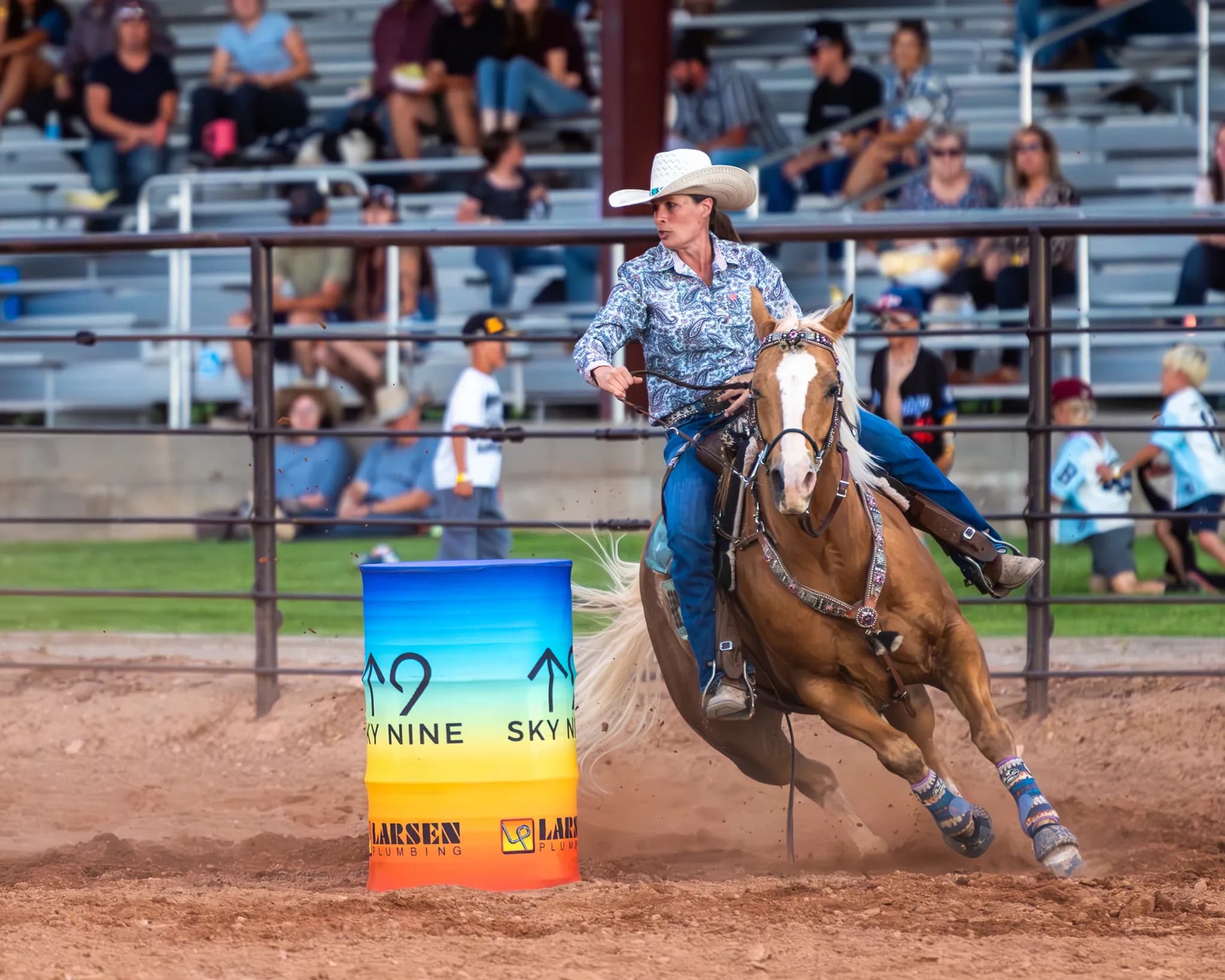 Barrel racer rounding a Sky 9 Events barrel in front of a full grandstand